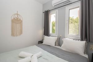 a white bedroom with a bed and two windows at Jasmine Suites "By Checkin" in Sisi