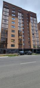 um grande edifício com carros estacionados em frente em Однокомнатная квартира в районе ЖК Аружан em Kokshetau