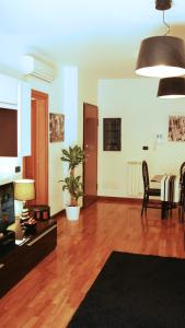 a living room with wooden floors and a table and chairs at Sweet Roman Holiday in Fiumicino