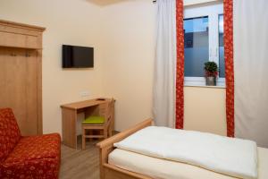 a bedroom with a bed and a chair and a window at Landhaus Storch - Pension in Gänserndorf