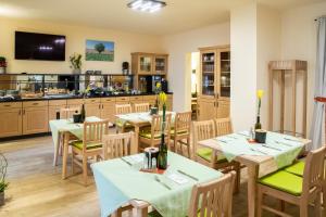 a restaurant with tables and chairs and a kitchen at Landhaus Storch - Pension in Gänserndorf