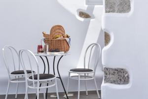 a table with chairs and a basket of food on it at Colours of Mykonos Luxury Residences & Suites in Psarou