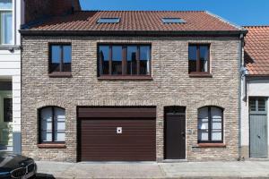 a brick house with a garage and windows at Gastenkamers Ten Huyze Marchandise in Bruges