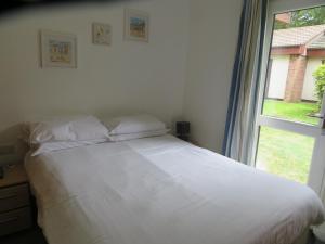 un letto bianco in una camera da letto con finestra di 11 Trevithick Court Tolroy Manor a Hayle