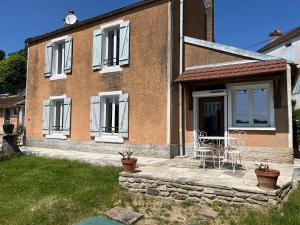 a brick house with a table and chairs on a patio at Le Verger Grimaldin in Grimault