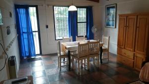 comedor con mesa, sillas y cortinas azules en ALOJAMIENTO SERRANO BIS en Villa Giardino