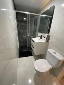a white bathroom with a toilet and a sink at Loft, muy cerca de playa y castillo Tamarit in Tarragona