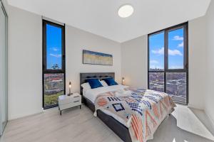 a white bedroom with a large bed and windows at Fully equipped apartment in Rockdale in Sydney
