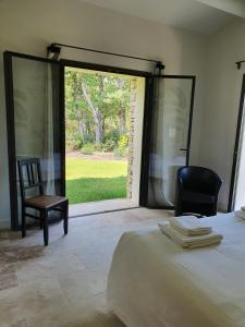 a bedroom with a bed and a chair and a window at L'Instant Luberon in Gordes