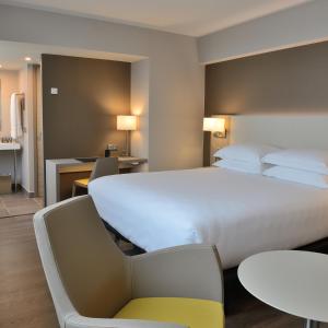 una habitación de hotel con una gran cama blanca y sillas en AC Hotel by Marriott Marseille Prado Vélodrome en Marsella