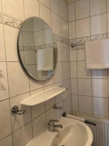 Baño blanco con lavabo y espejo en Landgasthaus zum Hirsch en Ramsen