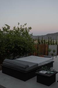 a bed on a patio with two tables at Casa Michaus Valle de Guadalupe in Valle de Guadalupe