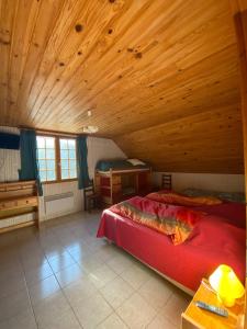 sypialnia z czerwonym łóżkiem i drewnianym sufitem w obiekcie Ferme-auberge le cochon du Madres w mieście Escouloubre
