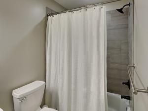 a bathroom with a white shower curtain and a toilet at Yes Deer in Oakland