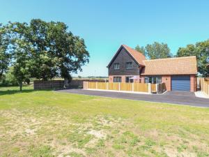 a detached house with a fence and a driveway at Oak Tree House, 1 Homestead Gardens in Filby