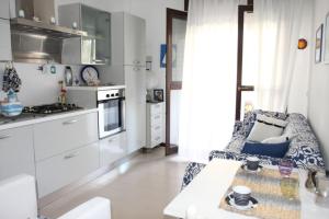 a kitchen with white cabinets and a chair at Nice Apartment only 150 metres from the Beach by Beahost Rentals in Bibione