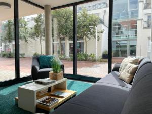 uma sala de estar com um sofá, uma mesa e janelas em Apartments Boardinghaus Norderney em Norderney