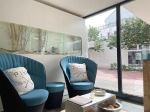 2 blaue Stühle in einem Zimmer mit Fenster in der Unterkunft Apartments Boardinghaus Norderney in Norderney