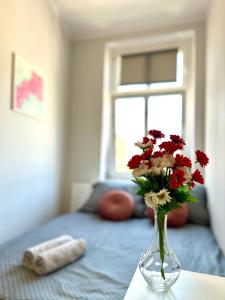 格但斯克的住宿－MMRent Wave Room，卧室里一张桌子上装有红白花的花瓶