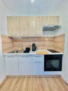 een keuken met witte kasten, een wastafel en een fornuis bij T2 Tête d’Or Confort + Parking gratuit in Villeurbanne