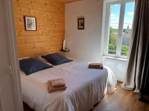 Un dormitorio con una cama con almohadas azules y una ventana en Le Verger Grimaldin, en Grimault