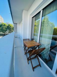 einen Balkon mit einem Holztisch und Stühlen auf einem Gebäude in der Unterkunft T2 Tête d’Or Confort + Parking gratuit in Villeurbanne
