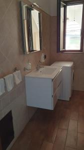 W łazience znajduje się biała umywalka i lustro. w obiekcie Domus Mariposa w mieście Tortolì