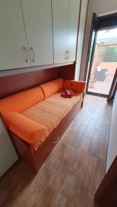 an orange couch in a room with a window at Domus Mariposa in Tortolì