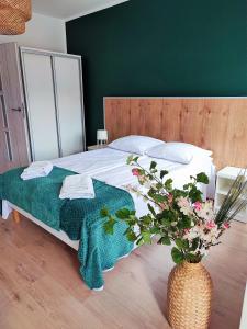 1 dormitorio con 1 cama y un jarrón con flores en Apartamenty Poddąbek en Poddąbie