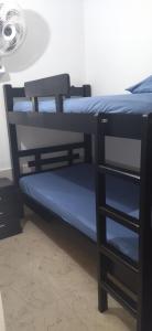 two bunk beds with blue sheets and a fan at Apartamento el Calamar in Cartagena de Indias