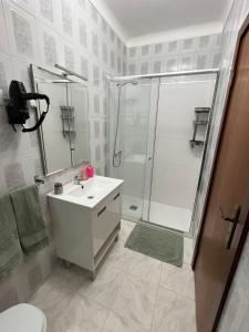 a white bathroom with a shower and a sink at Casas da Margarida in Vila Nova de Foz Coa