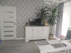 una sala de estar con TV en una cómoda blanca en Pokoje gościnne Słupy Olsztyn - parking, en Olsztyn