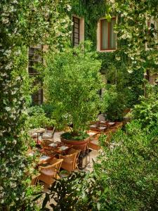 um jardim com mesas e cadeiras e uma árvore em The Rome EDITION em Roma