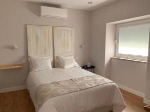 a bedroom with a large white bed with a window at Casa do Bairro in Seia
