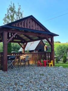 a wooden pavilion with a picnic table and chairs at Apartament u Jarząbków in Ciche