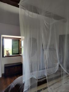 um quarto com uma cama com uma cortina branca em Ala Ovest de La Fabbrica in collina em Prasco