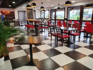 een restaurant met rode stoelen en tafels op een geruite vloer bij Kyriad Montluçon - Saint Victor in Saint-Victor