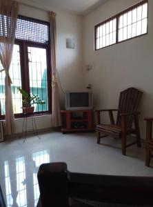 sala de estar con TV, silla y ventanas en Nature's Choice Homestay, en Panadura