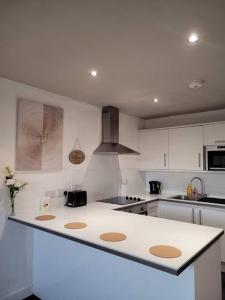 una cucina con armadi bianchi e piano di lavoro bianco di Astral 1 BR Flat in London AS36 a Norbury