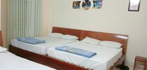 two beds in a room with white sheets and blue napkins at Quân Nguyễn in Vung Tau