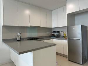 a kitchen with white cabinets and a stainless steel refrigerator at Luxury Condo Jalan Tun Razak in Kuala Lumpur