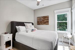 Schlafzimmer mit einem Bett mit weißer Bettwäsche und einem Fenster in der Unterkunft Whalers Paradise in Carolina Beach
