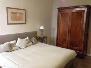 1 dormitorio con 1 cama blanca grande y armario de madera en Château Cornillon, en Arles