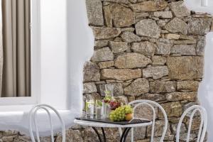 a table with two chairs and a stone wall at Colours of Mykonos Luxury Residences & Suites in Psarou