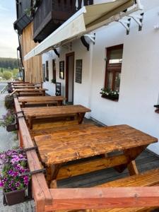 une rangée de tables en bois à l'extérieur d'un bâtiment dans l'établissement Kvildahotel, à Kvilda