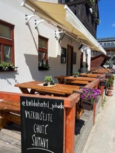 een restaurant met houten tafels en een bord ervoor bij Kvildahotel in Kvilda
