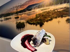 a piece of cake on a plate next to a lake at Kvildahotel in Kvilda