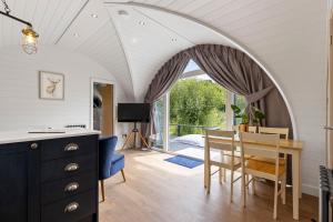 a dining room with an arched ceiling and a table and chairs at Nestledstays- The Lake House in Arundel