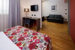 - une chambre avec un lit, un bureau et un canapé dans l'établissement Best Western Falck Village Milano Sesto, à Sesto San Giovanni