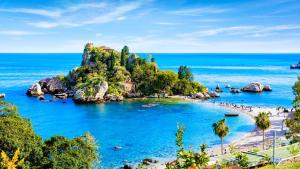 uma praia com uma ilha rochosa no oceano em Griseo - Sicily Holiday House em Misterbianco